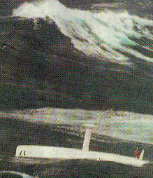 Newspaper photo of a sailor standing on the upturned hull of his boat in rough sea, a number 17 is visible on the side of the hull.